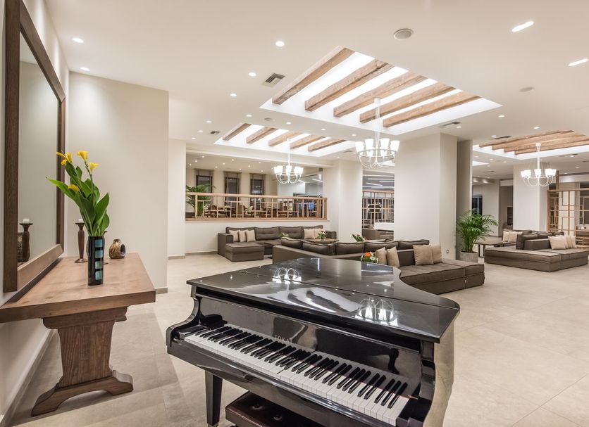 Nana Golden Beach in Hersonissos lobby with grand piano, seating areas, and skylit ceiling