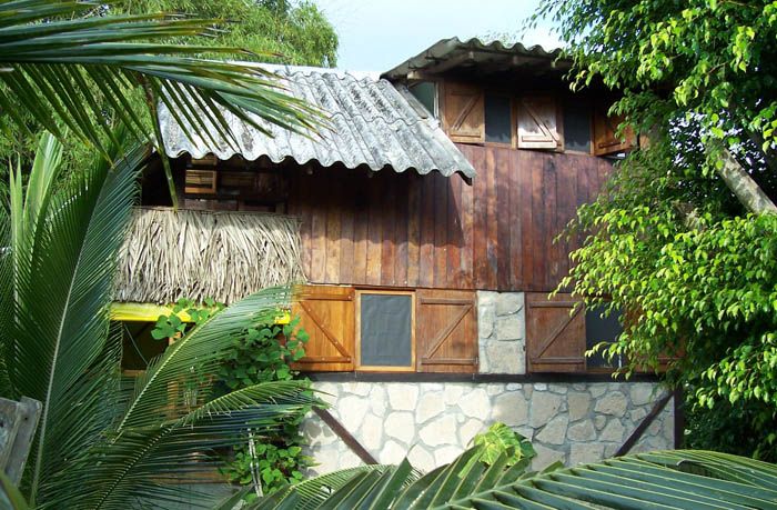 Hostal Oloncito in Olón, rustic wood-and-stone hotel exterior surrounded by lush tropical foliage