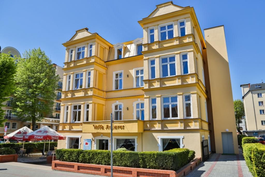 Villa Antares I & II in Świnoujście, yellow historic hotel building with bay windows and hedges