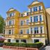 Villa Antares I & II in Świnoujście, yellow historic hotel building with bay windows and hedges