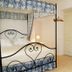 Ca' Ottocento in Lazise: wrought-iron four-poster bed, wall sconce, and white cabinet in a cozy room