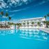Riu Playacar in Playa del Carmen with a large outdoor pool and palm trees under a blue sky