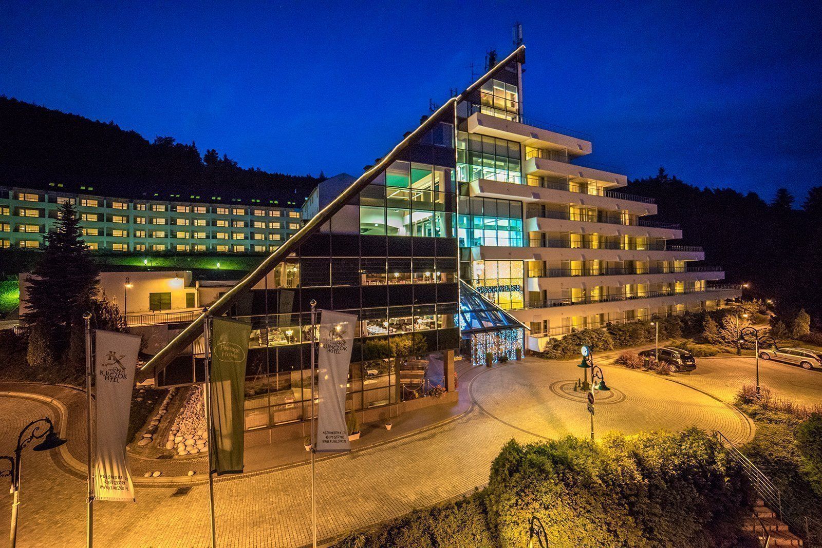 Hotel Klimczok Resort&Spa in Szczyrk at night, with a modern glass entrance and stepped balconies