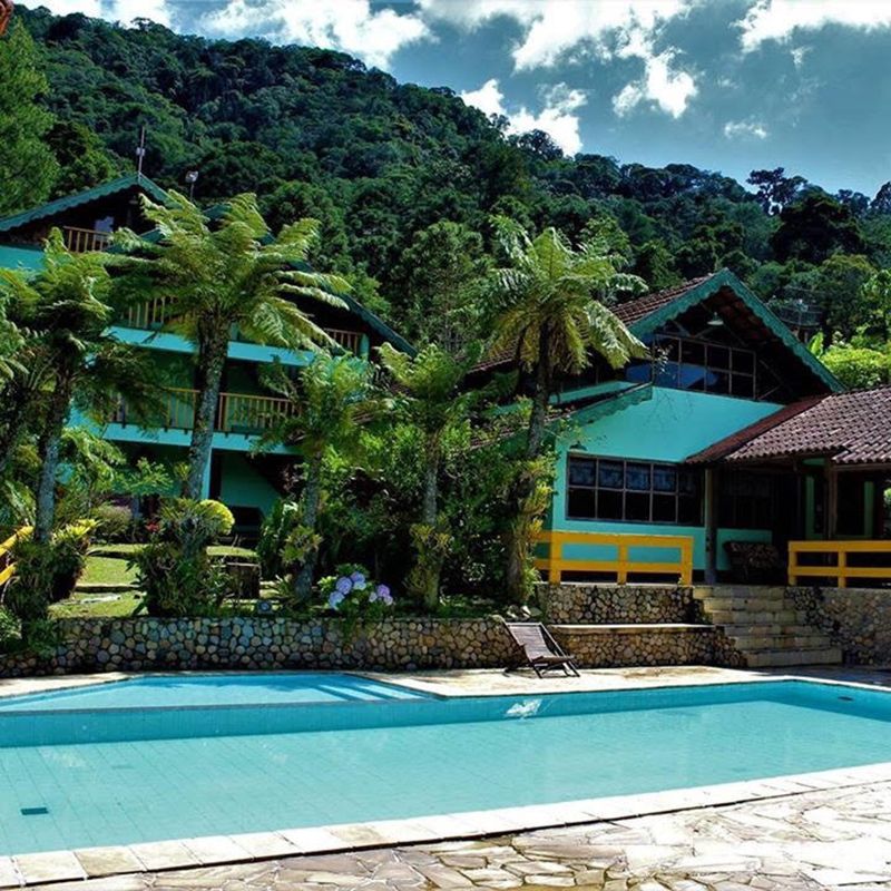 Hotel da Inês in Visconde de Maua with pool, tropical trees, and hillside backdrop