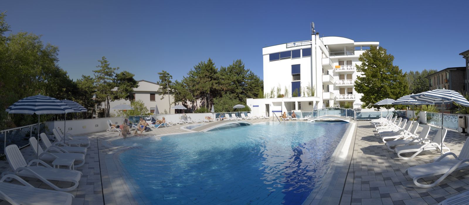 Hotel Firenze in Bibione with outdoor pool, sun loungers, and a white hotel building under a clear sky