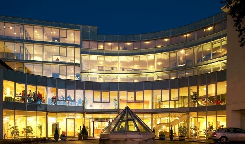 Amadeo Hotel Schaffenrath in Salzburg at night, with a curved glass facade glowing warmly