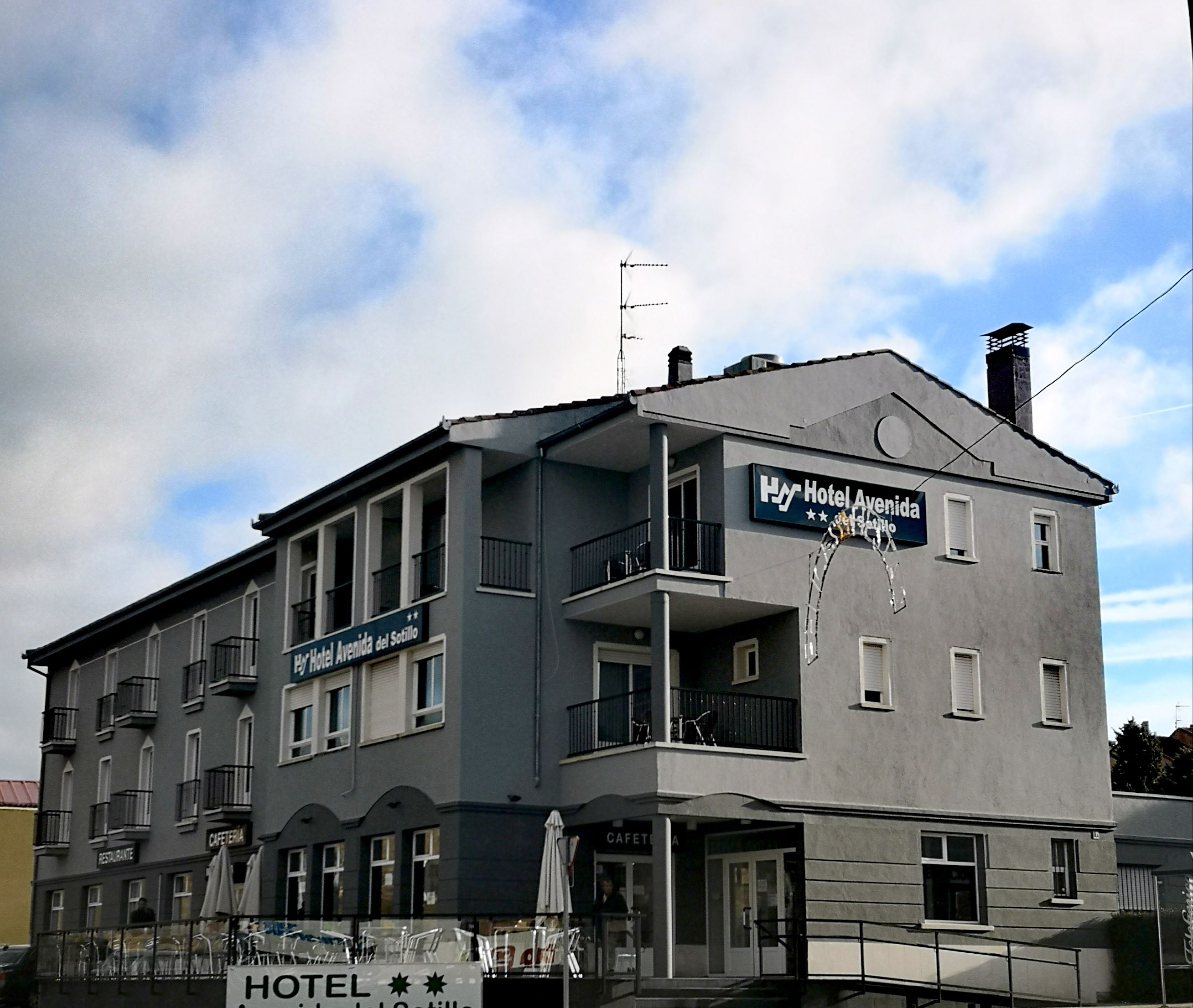 Hotel Avenida del Sotillo in Segovia, gray 2-story hotel exterior with balconies under a cloudy sky.