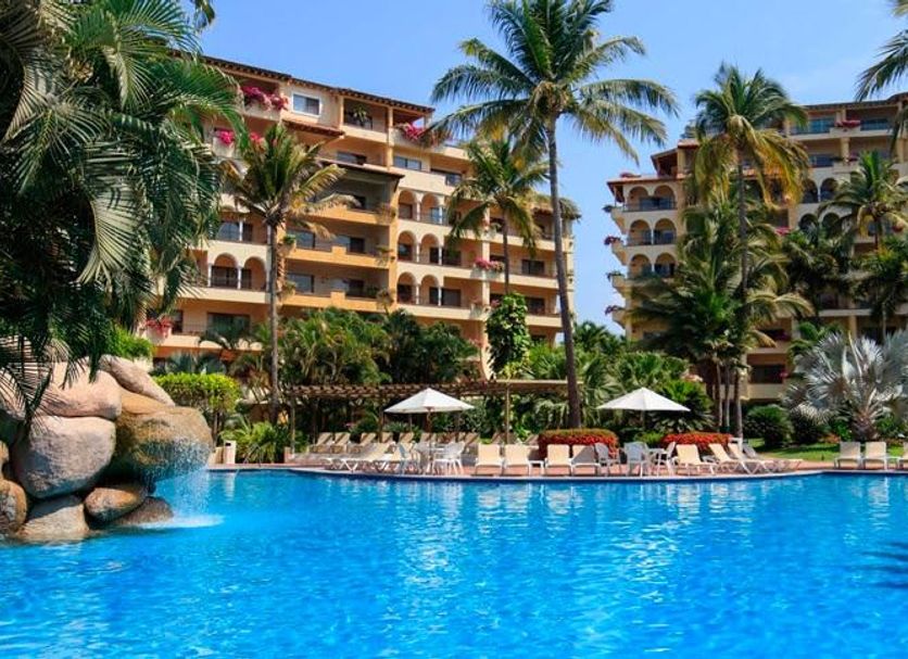 Velas Vallarta in Puerto Vallarta with a large blue pool, palm trees, and resort buildings