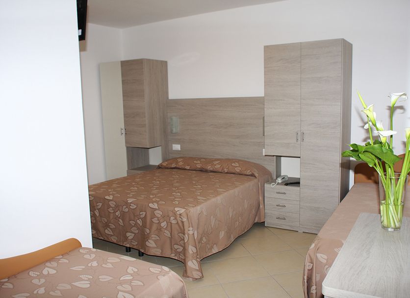 Hotel Villa Enea in Cattolica guest room with two beds, wood wardrobes, and a vase of flowers