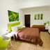 Cocoon Hotel in San José guest room with two beds, green accent chair and wall art