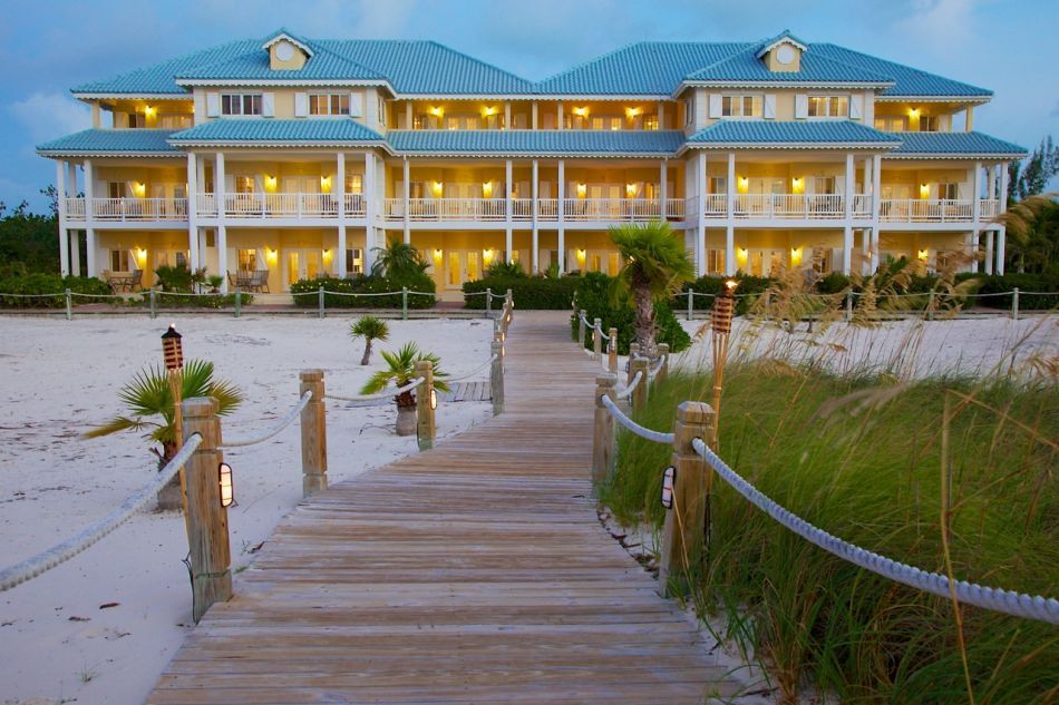 Beach House Turks and Caicos in Providenciales with beachfront boardwalk leading to a lit resort