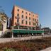 Hotel Riviera in Venice with a peach façade, green awnings, balconies and a flower-lined terrace