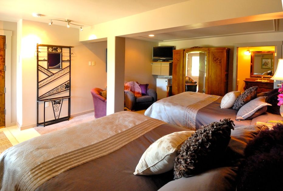 Swan River Inn in Bigfork guest room with two beds, armchair, and wood wardrobe
