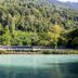The River Village in Interlaken with a lakeside building backed by lush forested mountains.