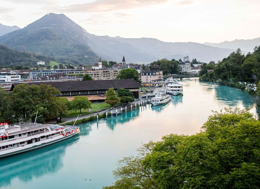 The River Village in Interlaken with riverboats on a turquoise river and mountain views