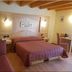 B&B La Montanara room in San Martino di Castrozza with double bed, sofa, and wooden beam ceiling