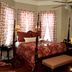1896 O'Malley House bedroom in New Orleans with four-poster bed, fireplace, and patterned curtains