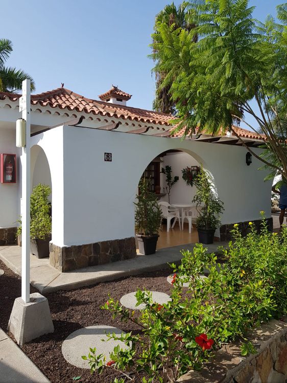 Parque Golf Bungalows in Maspalomas: white bungalow with terracotta roof, arched patio and palm trees