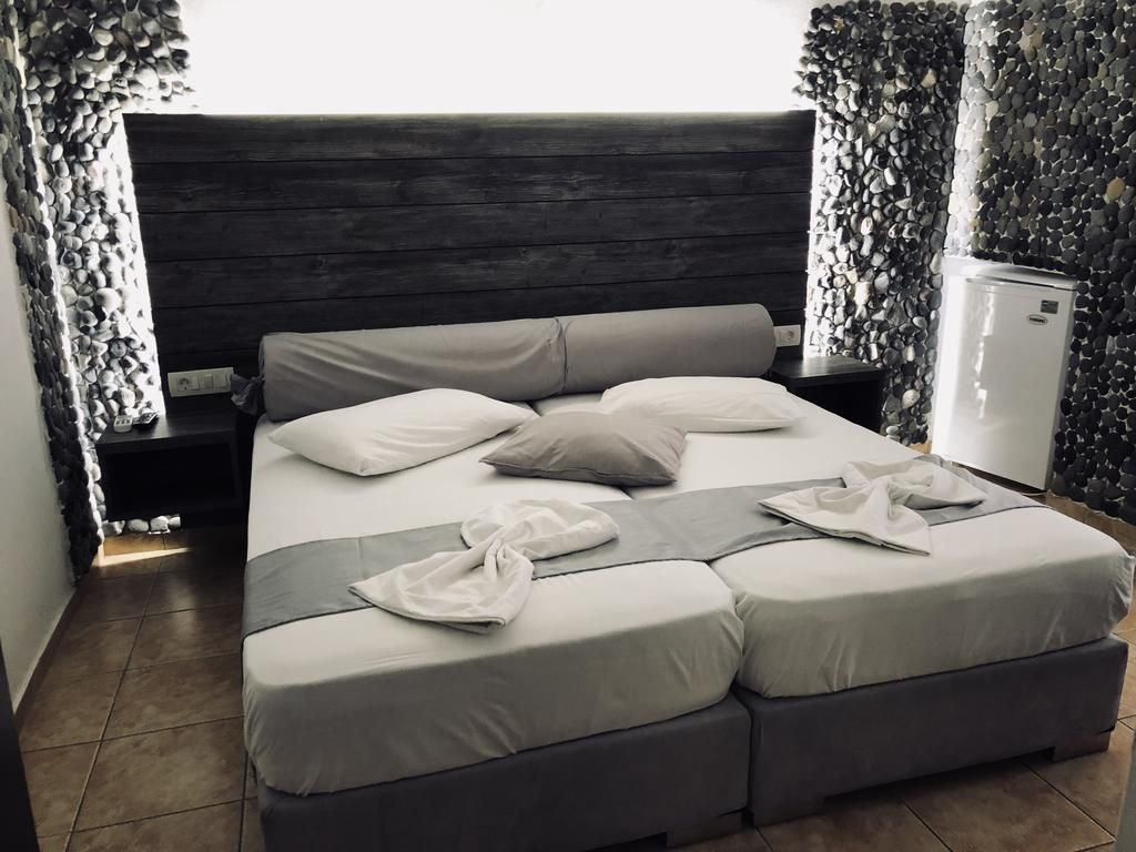 Villa Livadaros in Thera: double bed with dark headboard, side tables, and patterned wall panels