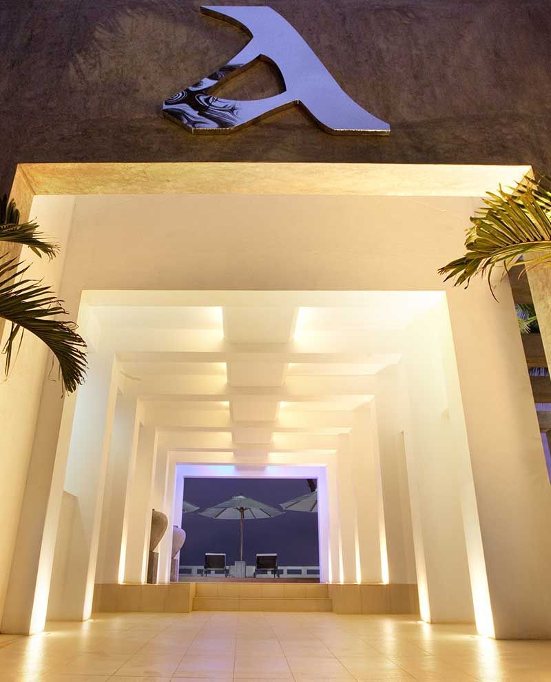 Cantaloupe Aqua in Talpe: illuminated corridor framing a beach lounge with umbrella and chairs