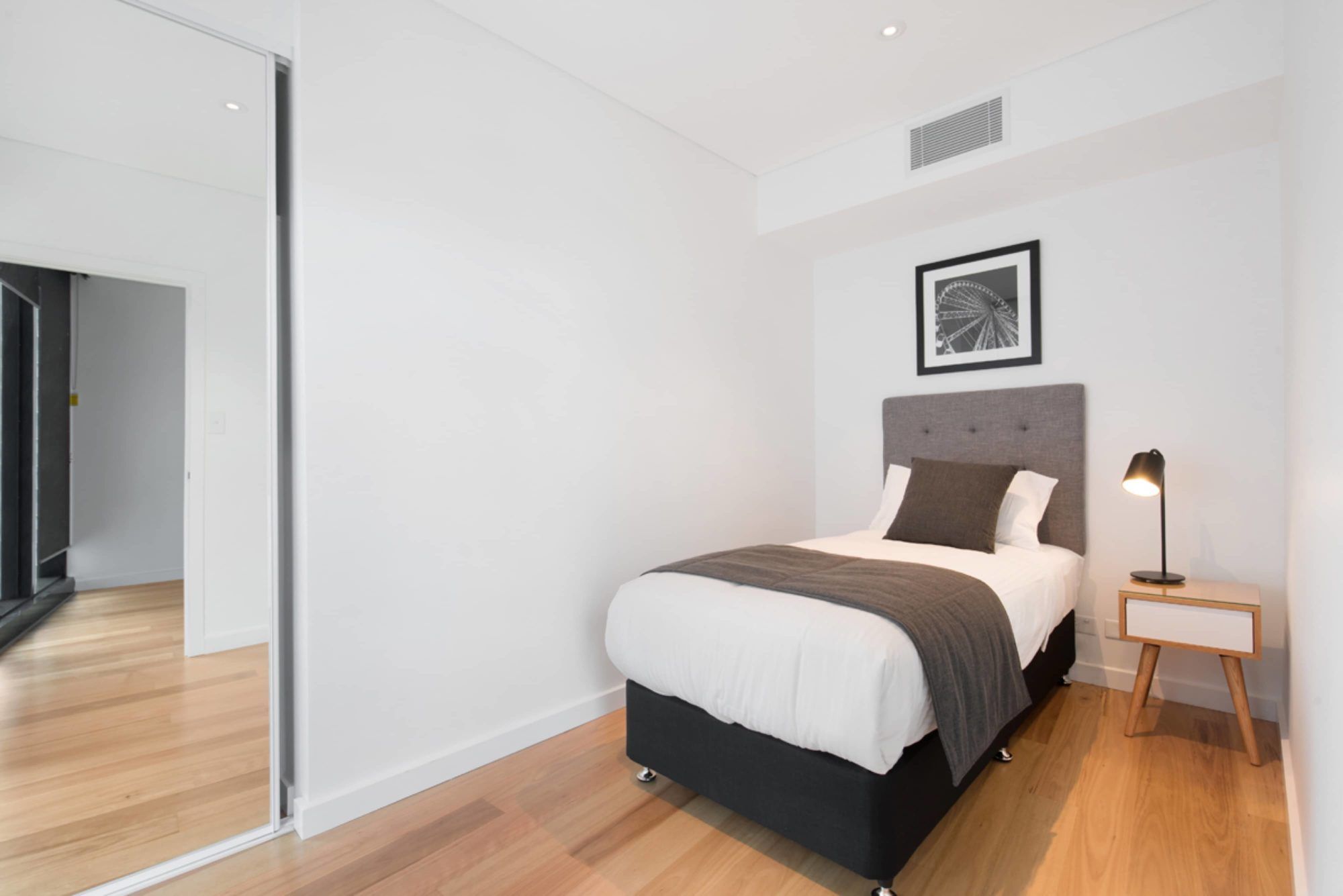 Brisbane Skytower hotel room with single bed, bedside lamp and mirrored wardrobe in Brisbane