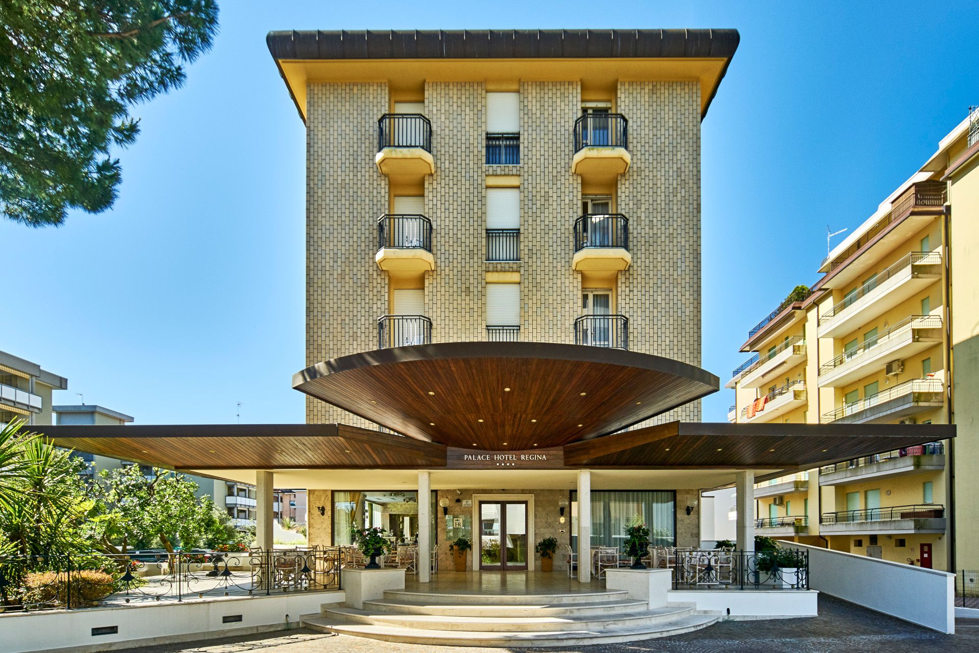 Palace Hotel Regina in Bibione, exterior with curved entrance canopy and balconies