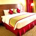 Rayan Hotel Sharjah in Sharjah guest room with a large bed, red accents, chair, and side table