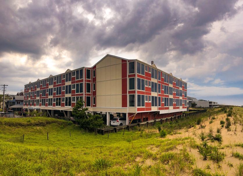 Surf Club Oceanfront Hotel in Rehoboth Beach beside dunes and beach under a cloudy sky