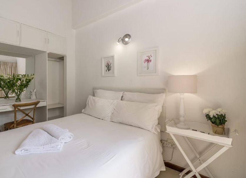 Green Park Manor Johannesburg bedroom with white bed, bedside lamp, vanity mirror and flowers