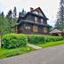 Willa Jarowit in Zakopane, a dark wooden lodge with green hedges, driveway, and pine trees