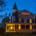 Ivy Lodge in Newport, Victorian inn with wraparound porch and turret lit at dusk
