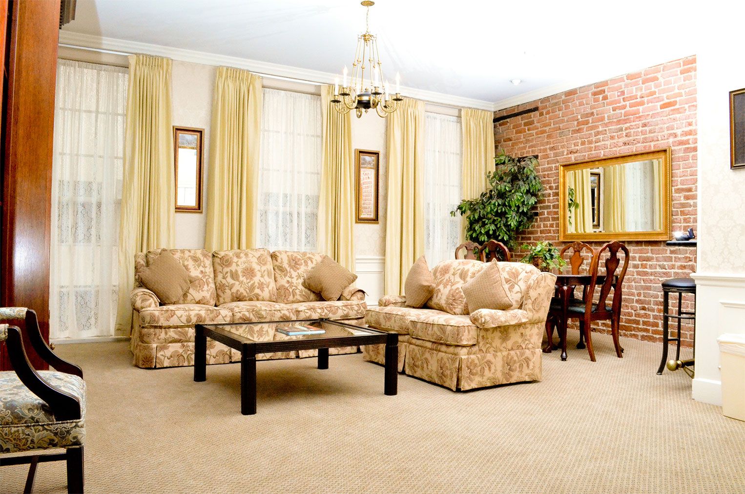 Quarter House Suites in New Orleans living room with sofas, coffee table, chandelier, and brick accent wall