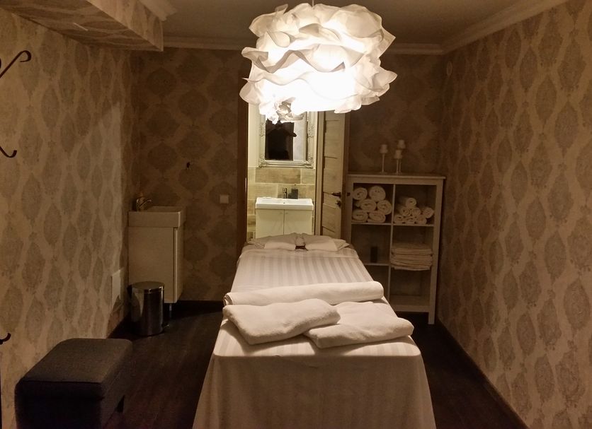 Inza Guest House in Druskininkai spa treatment room with massage table and towel shelves