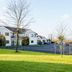 Foxfields Country Hotel in Clitheroe with a grassy lawn, bare trees, and parking area