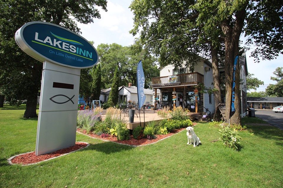Lakes Inn in Detroit Lakes sign, landscaped lawn, outdoor patio, and lakeside building exterior.