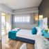 Prima City Hotel Tel Aviv room with bed, sofa, wall-mounted TV and balcony view