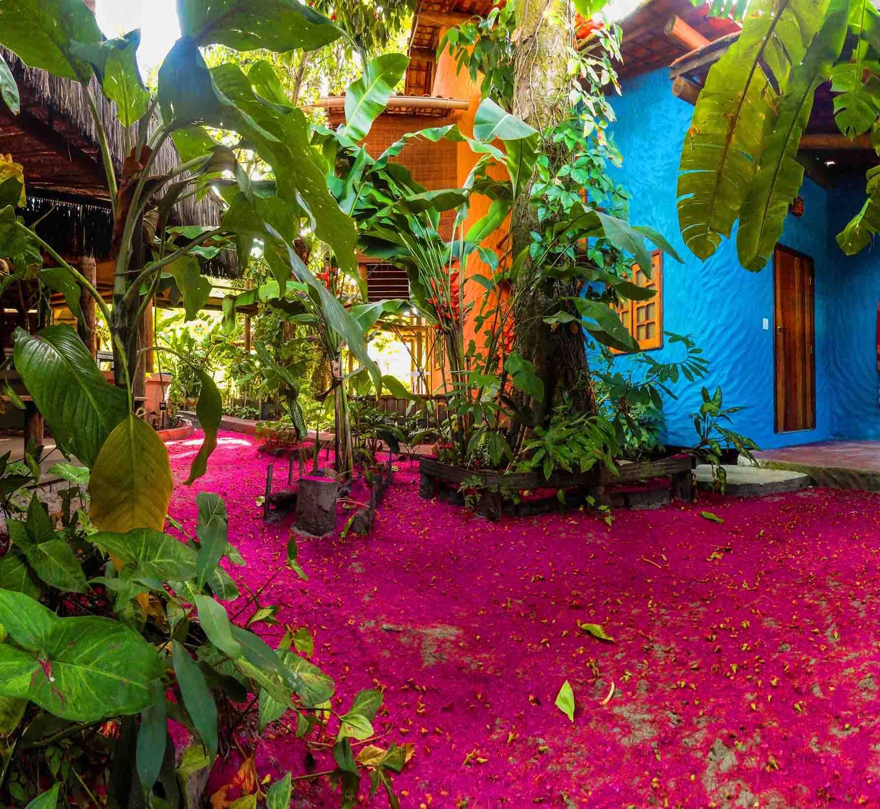 Pousada Aldeia in Velha Boipeba, tropical courtyard with lush greenery and vivid pink ground