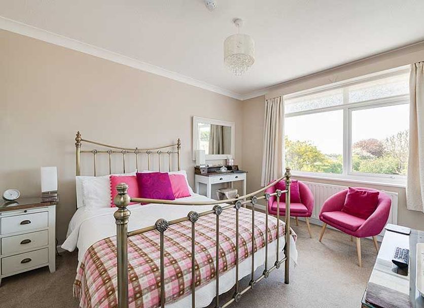 The Coast Yard B & B and Garden Chalets bedroom in Chichester with brass bed, pink chairs and garden view