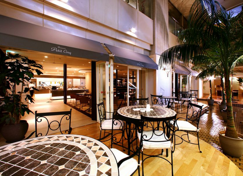 Hotel Centraza Hakata in Fukuoka patio with outdoor tables, palm trees, and café entrance