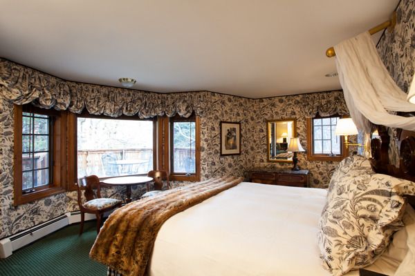 Christiania Lodge in Vail guest room with large windows, mountain-view seating area, and canopy bed