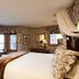 Christiania Lodge in Vail guest room with large windows, mountain-view seating area, and canopy bed