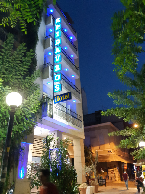 Epidavros Hotel in Athens exterior at night with blue neon sign and tree-lined street