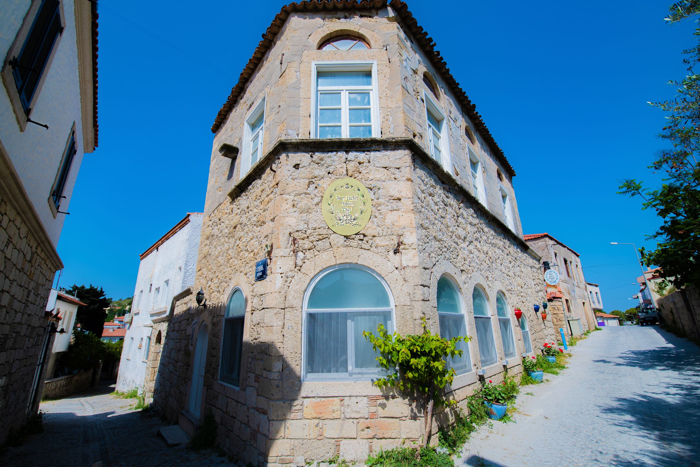 Sari Gelin Alacati Hotel in Alacati, stone facade building on a sunny street