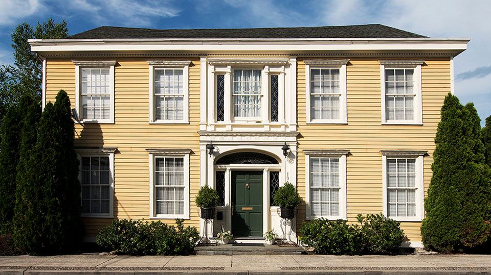 Hudson B&B in Hudson, yellow colonial-style hotel exterior with black shutters and central entrance