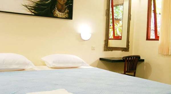 Maapun in Ubud room with bed, wall art, desk, chair and windows with greenery outside