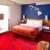 Shoreline Hotel Waikiki room in Honolulu with colorful bed, blue accent wall, and balcony door