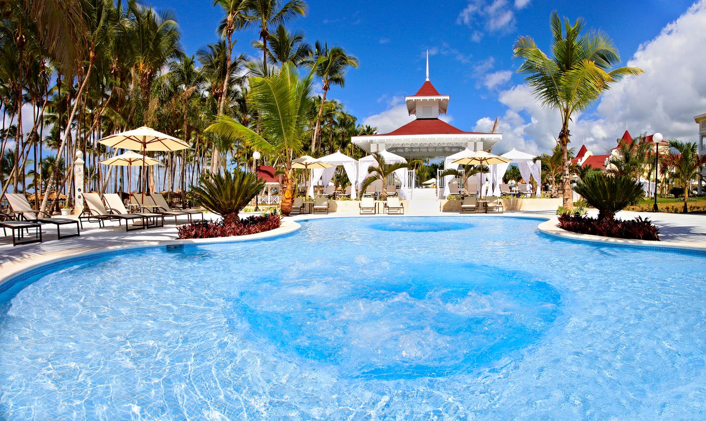 Bahia Principe Luxury Bouganville in La Romana features a tropical pool with palm trees and loungers.