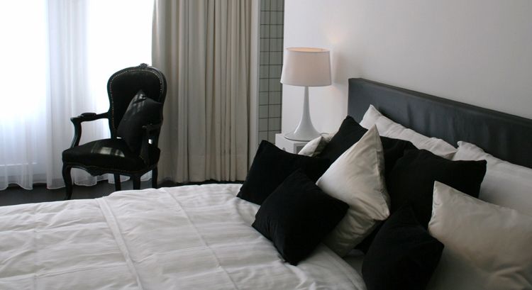 Hotel Esperance Brussels guest room with bed, black chair, bedside lamp and curtains