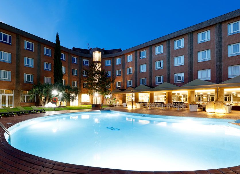 Hotel SB Corona Tortosa in Tortosa with a glowing outdoor pool and lit courtyard at dusk