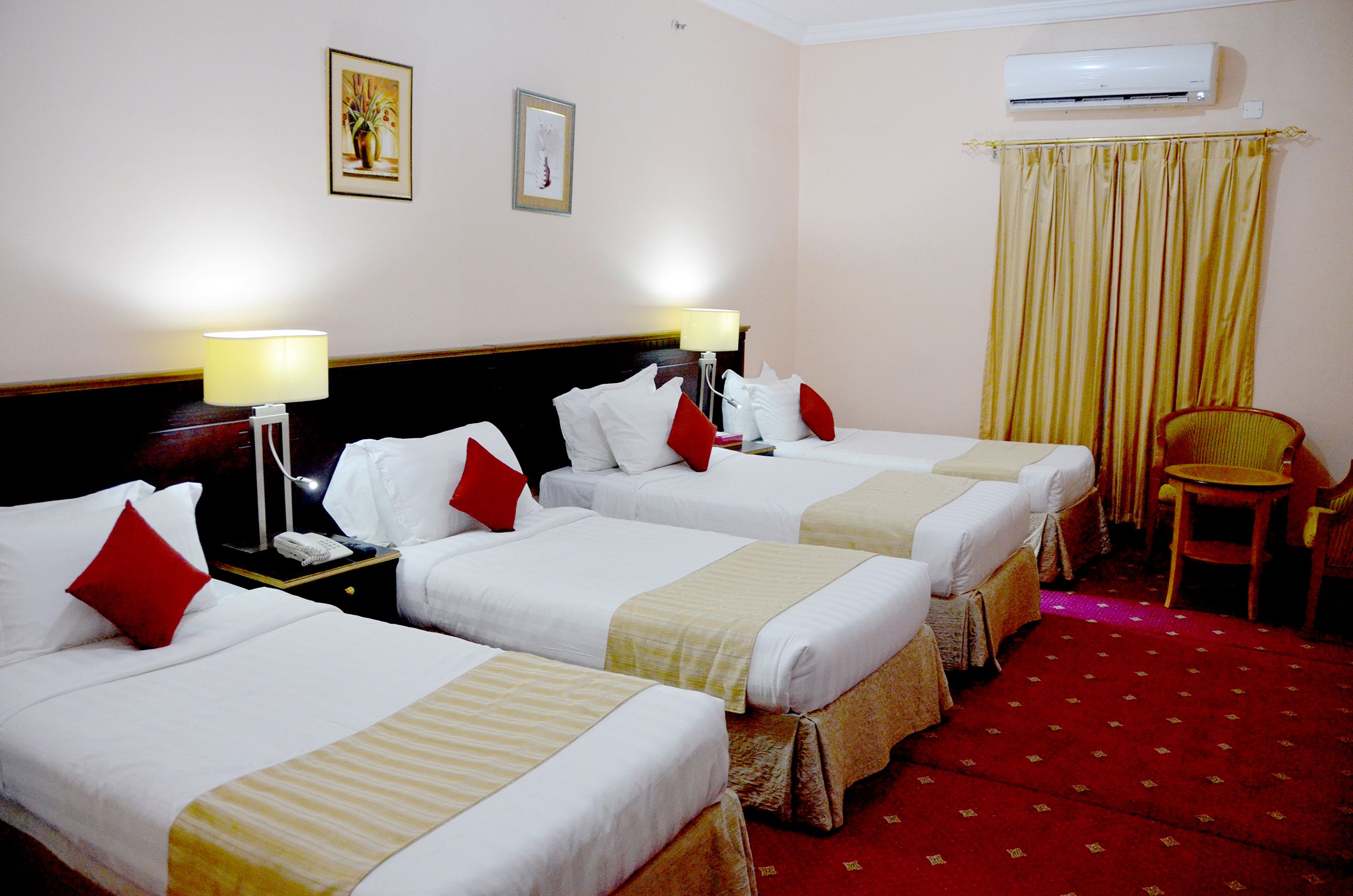 Safeer almisk Hotel in Mecca guest room with three single beds, desk, curtains and wall art